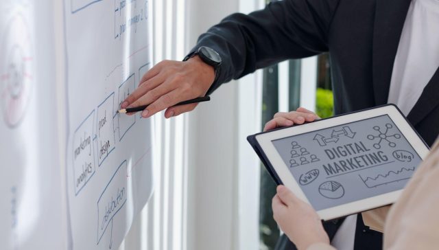 Team planning a campaign on a whiteboard while reviewing a “Digital Marketing” tablet, work led by a Digital Marketing Company in Dallas to build day-one visibility.