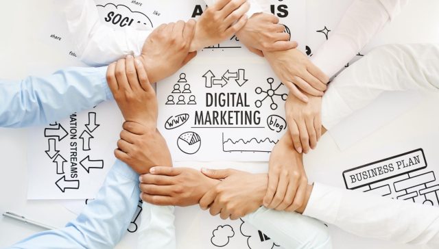 Marketing team linking hands over strategy sketches labeled “Digital Marketing,” illustrating what are the 4 types of digital marketing for movers.