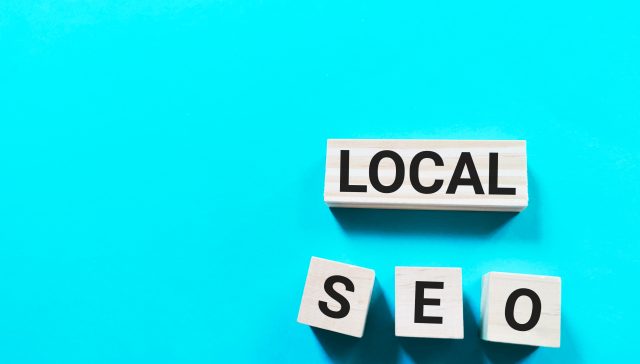Wooden blocks spelling out "LOCAL SEO" on a bright aqua blue background, representing local search engine optimization.