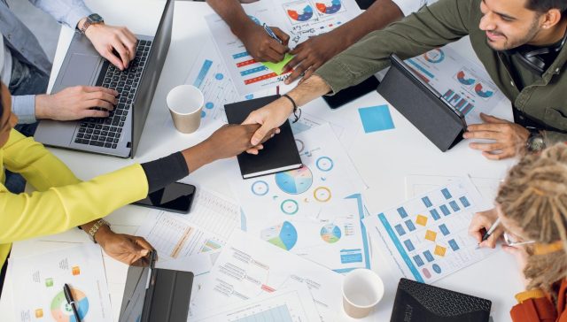 Agency team shaking hands over marketing reports while reviewing white label SEO performance data